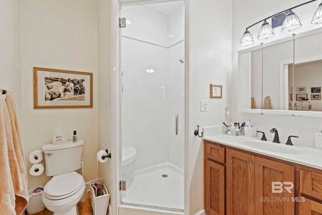 bathroom with toilet, a stall shower, and vanity