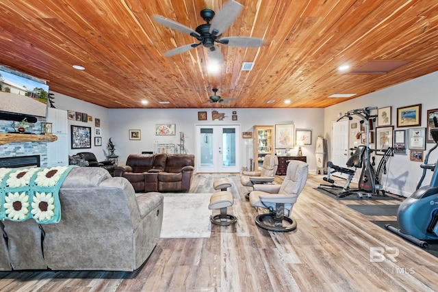 living area with french doors, visible vents, wood ceiling, a stone fireplace, and wood finished floors