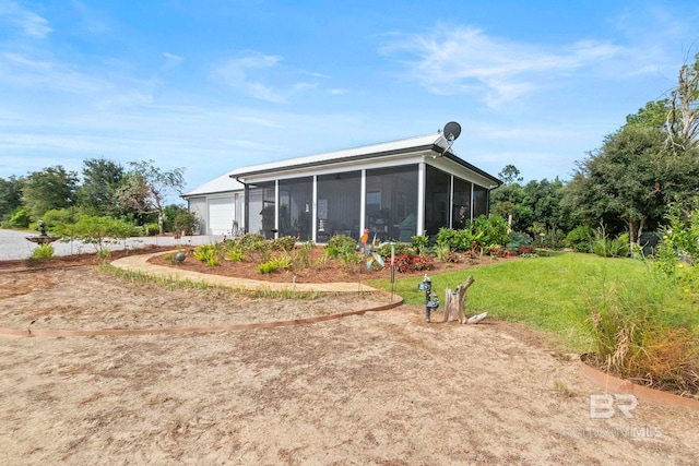 exterior space with a yard, an attached garage, and a sunroom