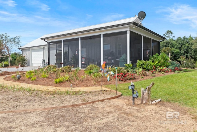 back of house with an attached garage and a sunroom