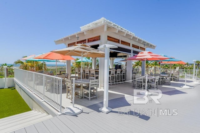 view of community featuring outdoor dining space, a wooden deck, and fence