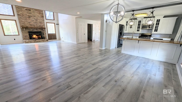 kitchen with pendant lighting, wood counters, backsplash, black appliances, and a fireplace