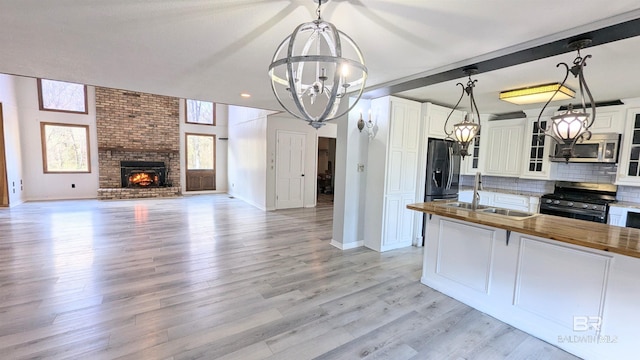 kitchen with butcher block countertops, sink, white cabinets, and stainless steel appliances