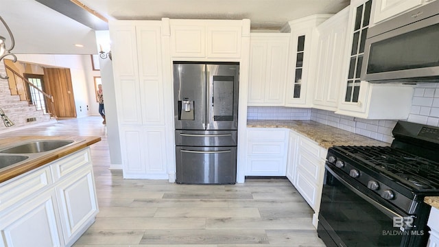 kitchen with light stone countertops, sink, stainless steel appliances, decorative backsplash, and white cabinets