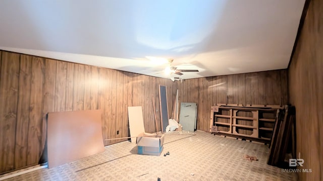 spare room featuring ceiling fan and wood walls