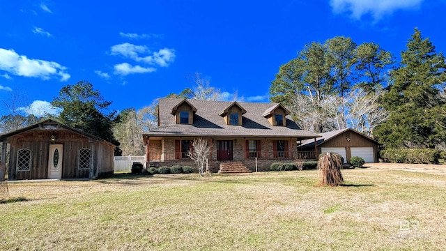 view of front facade with covered porch, a garage, an outbuilding, and a front yard