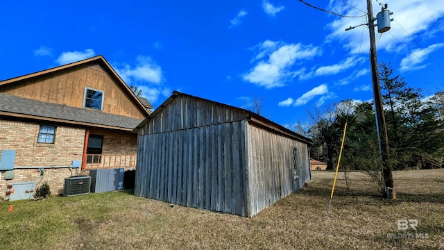 view of property exterior with a lawn, central air condition unit, and an outdoor structure