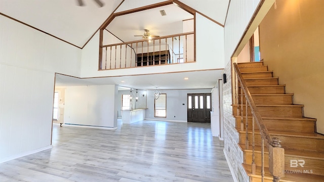 interior space featuring ceiling fan, light hardwood / wood-style floors, and a high ceiling