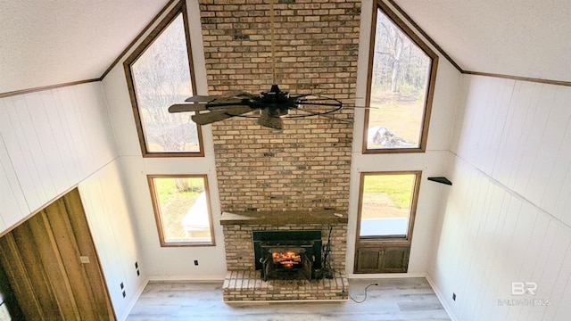 unfurnished living room with light wood-type flooring, a textured ceiling, a brick fireplace, and a wealth of natural light