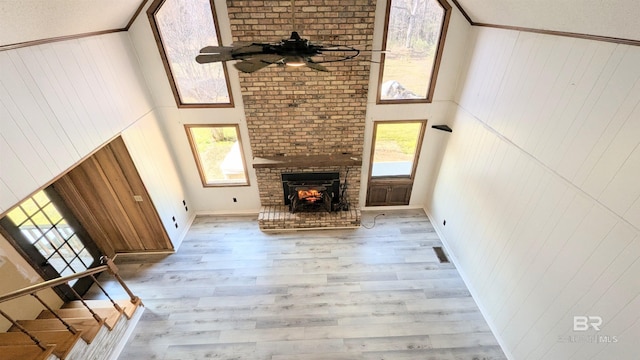 unfurnished living room with ceiling fan, a healthy amount of sunlight, light wood-type flooring, and a high ceiling