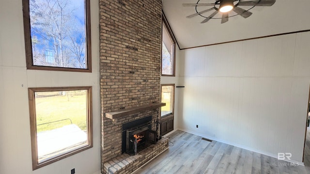 unfurnished living room featuring ceiling fan, plenty of natural light, vaulted ceiling, and light wood-type flooring