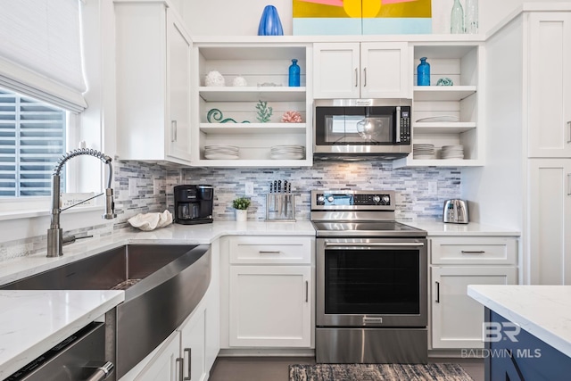 kitchen featuring sink, appliances with stainless steel finishes, light stone counters, white cabinets, and decorative backsplash