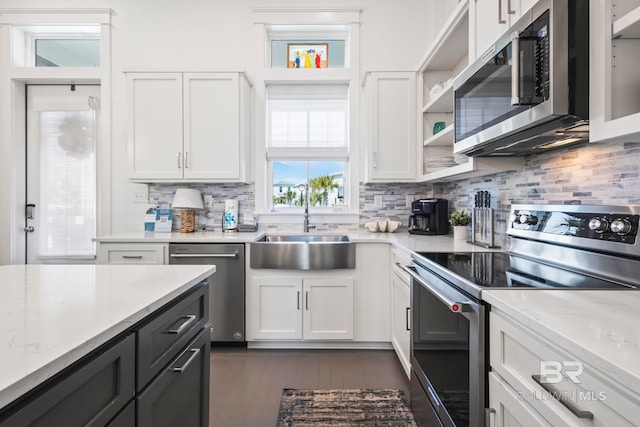 kitchen featuring sink, white cabinetry, appliances with stainless steel finishes, light stone countertops, and decorative backsplash