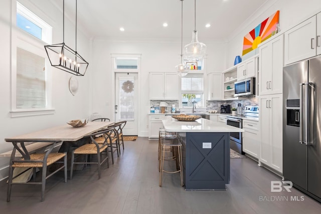 kitchen featuring pendant lighting, appliances with stainless steel finishes, a center island, and white cabinets