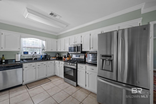 kitchen featuring sink, light tile patterned floors, appliances with stainless steel finishes, white cabinets, and ornamental molding