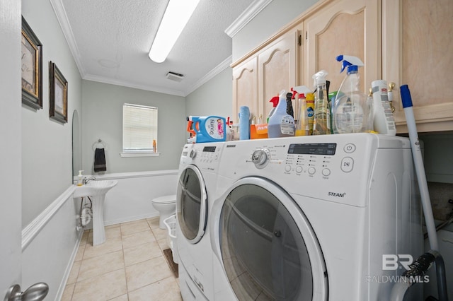 laundry room featuring crown molding, washer and clothes dryer, light tile patterned floors, and a textured ceiling