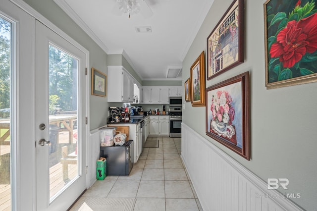 interior space with white cabinets, ceiling fan, ornamental molding, appliances with stainless steel finishes, and light tile patterned flooring