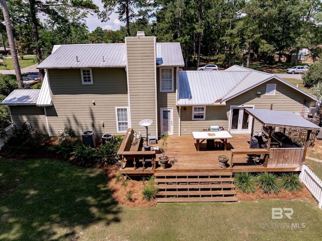 back of property featuring a deck and a lawn