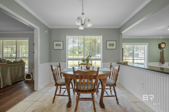 tiled dining room featuring a healthy amount of sunlight, crown molding, and a chandelier