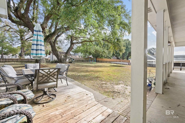 10197 Bellingrath Rd, Theodore, AL 36582 - wooden terrace featuring a trampoline, outdoor dining space, and a fenced backyard