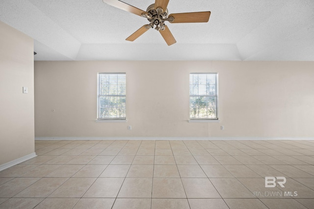 spare room with a raised ceiling, ceiling fan, light tile patterned flooring, and a textured ceiling