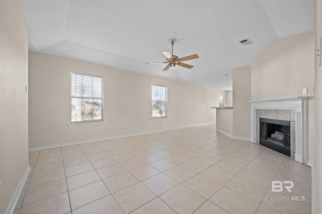 unfurnished living room with light tile patterned floors, vaulted ceiling, ceiling fan, and a tiled fireplace