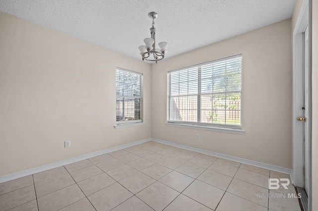 unfurnished room featuring a notable chandelier, light tile patterned flooring, and a textured ceiling