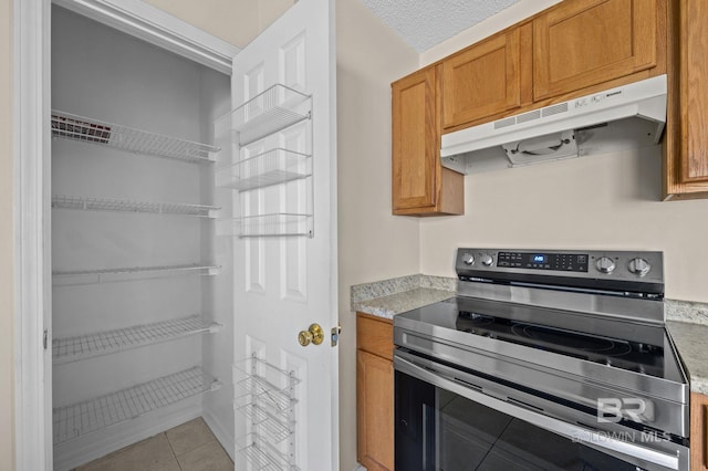 kitchen with electric stove, a textured ceiling, and light tile patterned floors