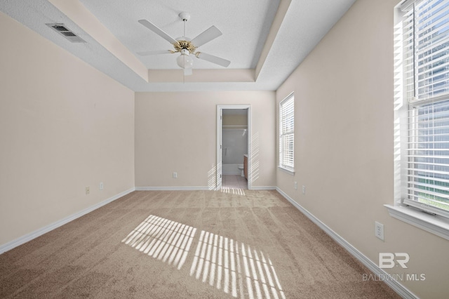 unfurnished bedroom featuring ceiling fan, a raised ceiling, a textured ceiling, and light carpet