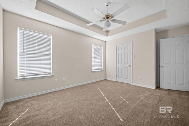 unfurnished bedroom featuring ceiling fan, a textured ceiling, and a tray ceiling