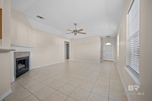 unfurnished living room featuring ceiling fan, a fireplace, light tile patterned flooring, and vaulted ceiling