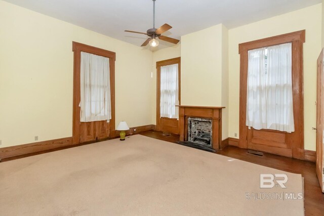 unfurnished living room with a healthy amount of sunlight, ceiling fan, and dark hardwood / wood-style floors