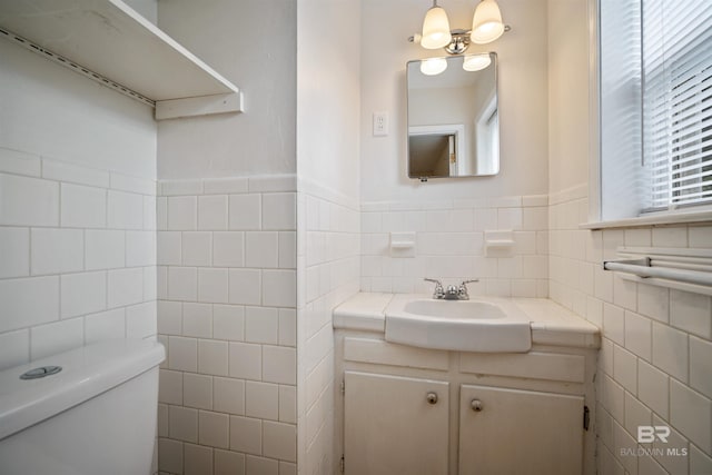 bathroom with a chandelier, vanity, toilet, and tile walls