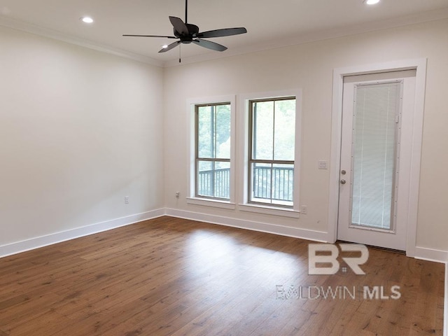 empty room featuring ceiling fan, crown molding, and dark wood-type flooring