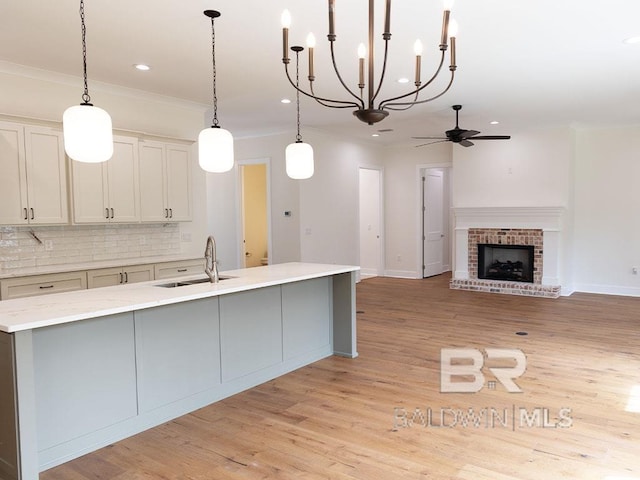 kitchen with ceiling fan, sink, pendant lighting, decorative backsplash, and a fireplace