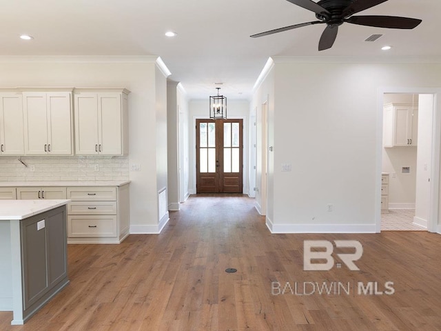 entryway with ceiling fan with notable chandelier, light wood-type flooring, and crown molding