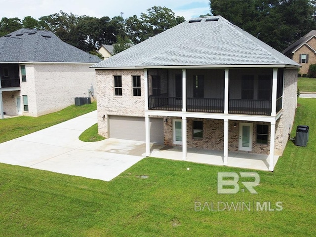 back of property featuring central air condition unit, a sunroom, a lawn, and a garage