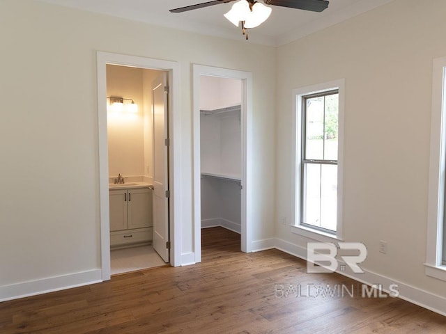 unfurnished bedroom with ceiling fan, sink, a spacious closet, dark hardwood / wood-style floors, and ensuite bathroom