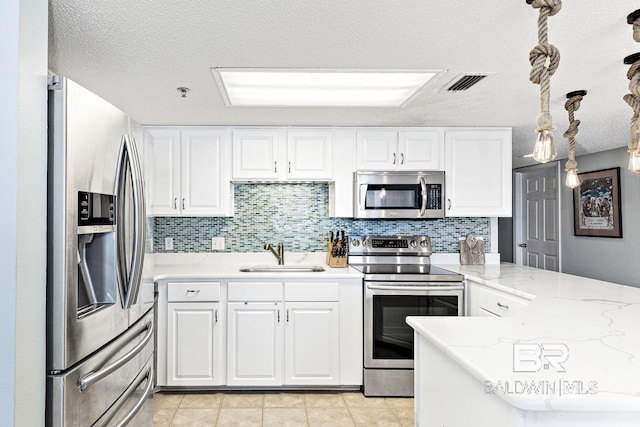 kitchen with white cabinets, appliances with stainless steel finishes, a sink, a peninsula, and visible vents