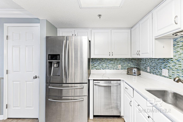 kitchen with light stone countertops, stainless steel appliances, and white cabinetry