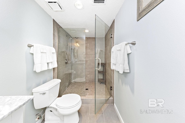 full bath featuring vanity, toilet, a textured ceiling, visible vents, and a stall shower