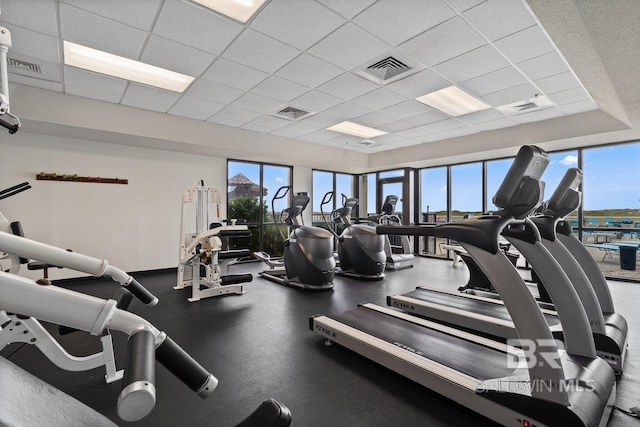 exercise room featuring plenty of natural light, a drop ceiling, and visible vents