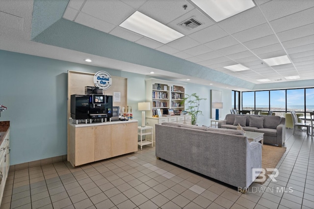living area with visible vents, baseboards, a paneled ceiling, and light tile patterned floors