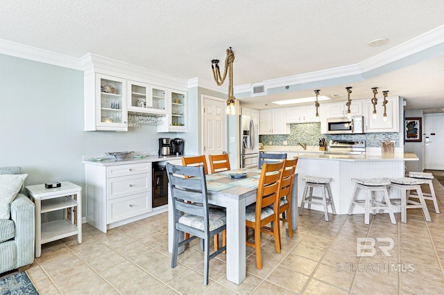 dining room with crown molding, a textured ceiling, light tile patterned floors, and visible vents