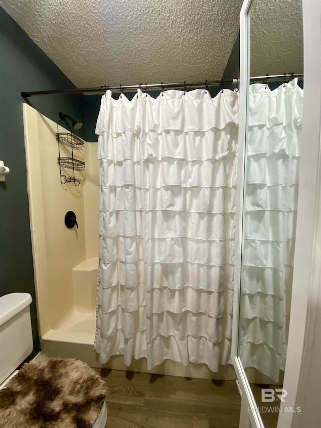 bathroom with toilet, a shower with curtain, hardwood / wood-style flooring, and a textured ceiling