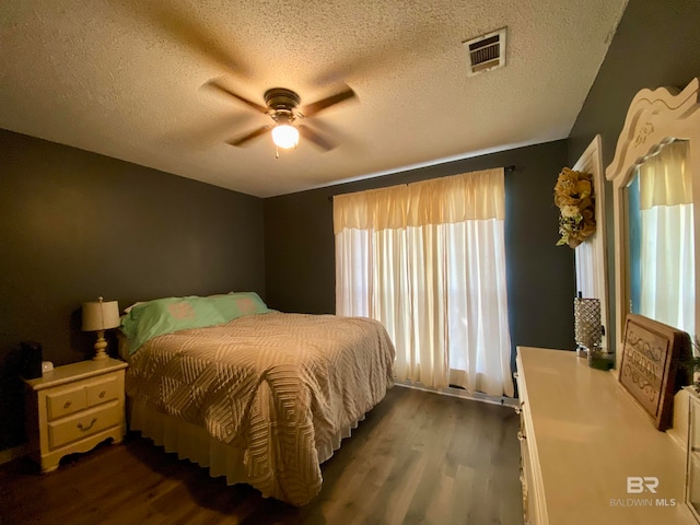 bedroom with a textured ceiling, ceiling fan, and dark hardwood / wood-style flooring