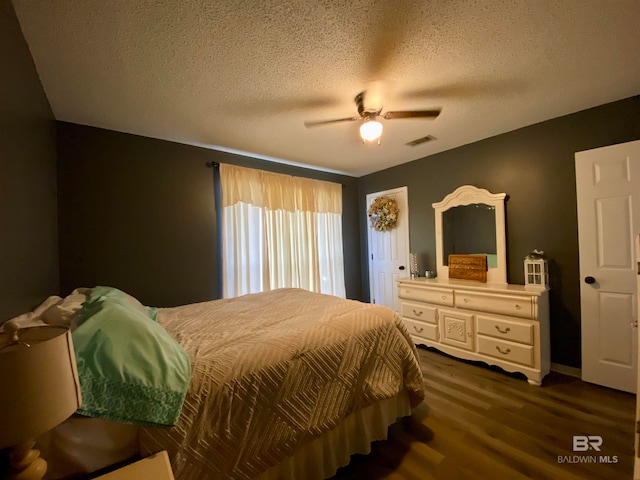 bedroom with dark wood-type flooring, a textured ceiling, and ceiling fan