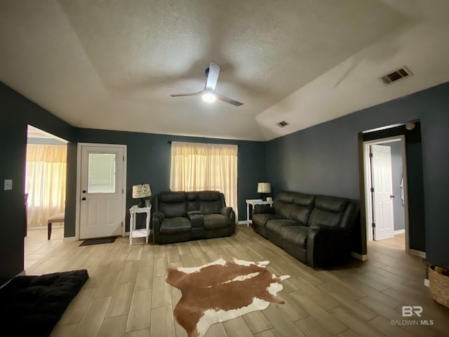 living room featuring a textured ceiling, light hardwood / wood-style flooring, ceiling fan, and vaulted ceiling