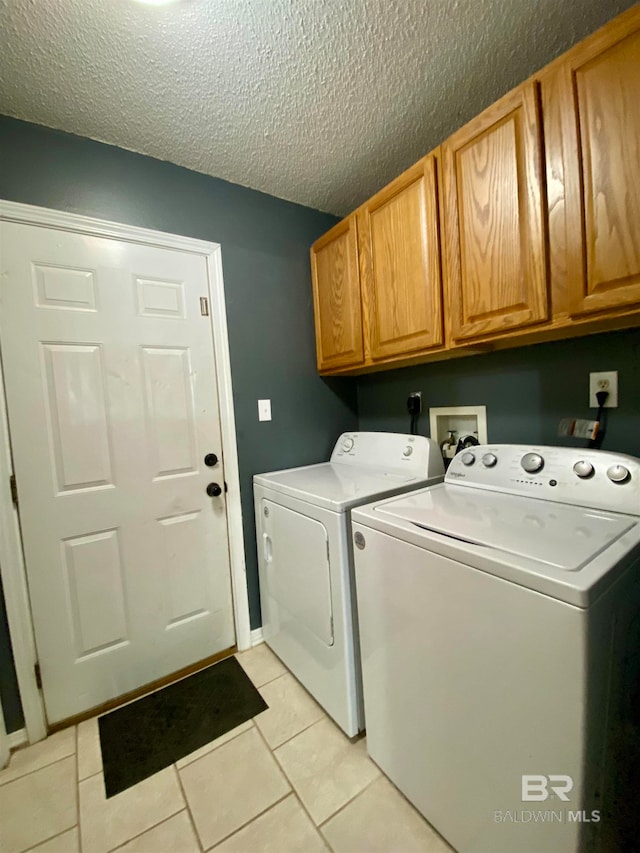 washroom featuring light tile patterned floors, a textured ceiling, cabinets, and washer and dryer