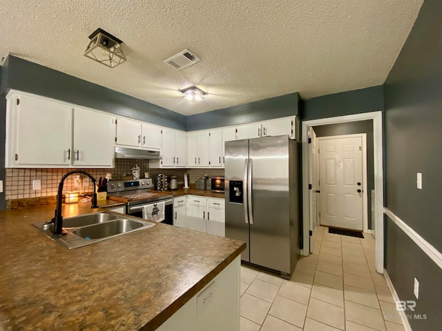 kitchen with a textured ceiling, stainless steel appliances, white cabinets, and tasteful backsplash